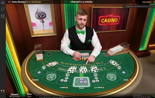 Krupiér Hry Blackjack při rozdávání karet v online kasinu. Krupiér u stolu Hry Blackjack rozdává karty hráčům během hry.